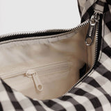 Baggu Meringue Bag Small - Black and Cream Gingham. Close-up of checkered nylon bag with silver metal zipper, and view of cream interior lining with pocket.