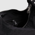 Baggu Meringue Bag Small - Studs. Close-up of black nylon bag with silver metal zipper, and view of black interior lining with pocket.