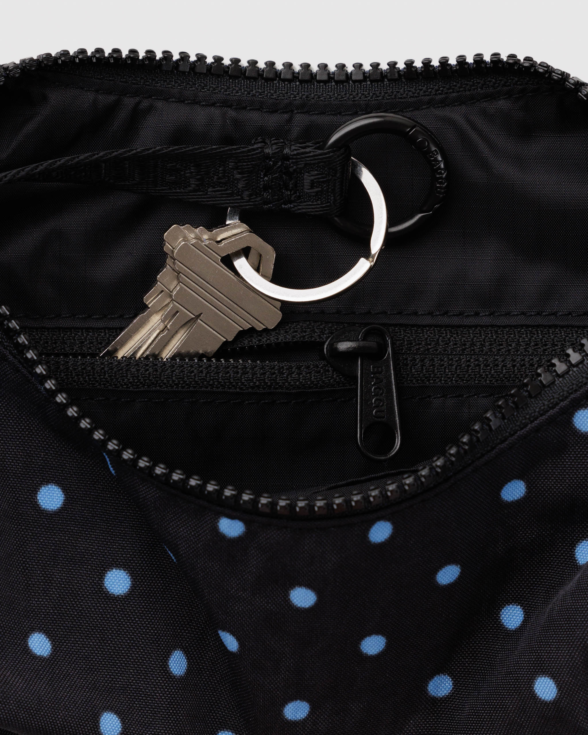 Baggu Crescent Bag Small - Black and Sky Blue Micro Dot. Close up view of interior lining with internal zip and keychain holder. 