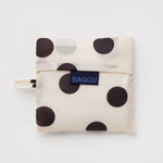 Standard Baggu Bag -  Black and Cream Polka Dot. Reusable shopping tote folded up in its compact square case with 'BAGGU" logo tag.