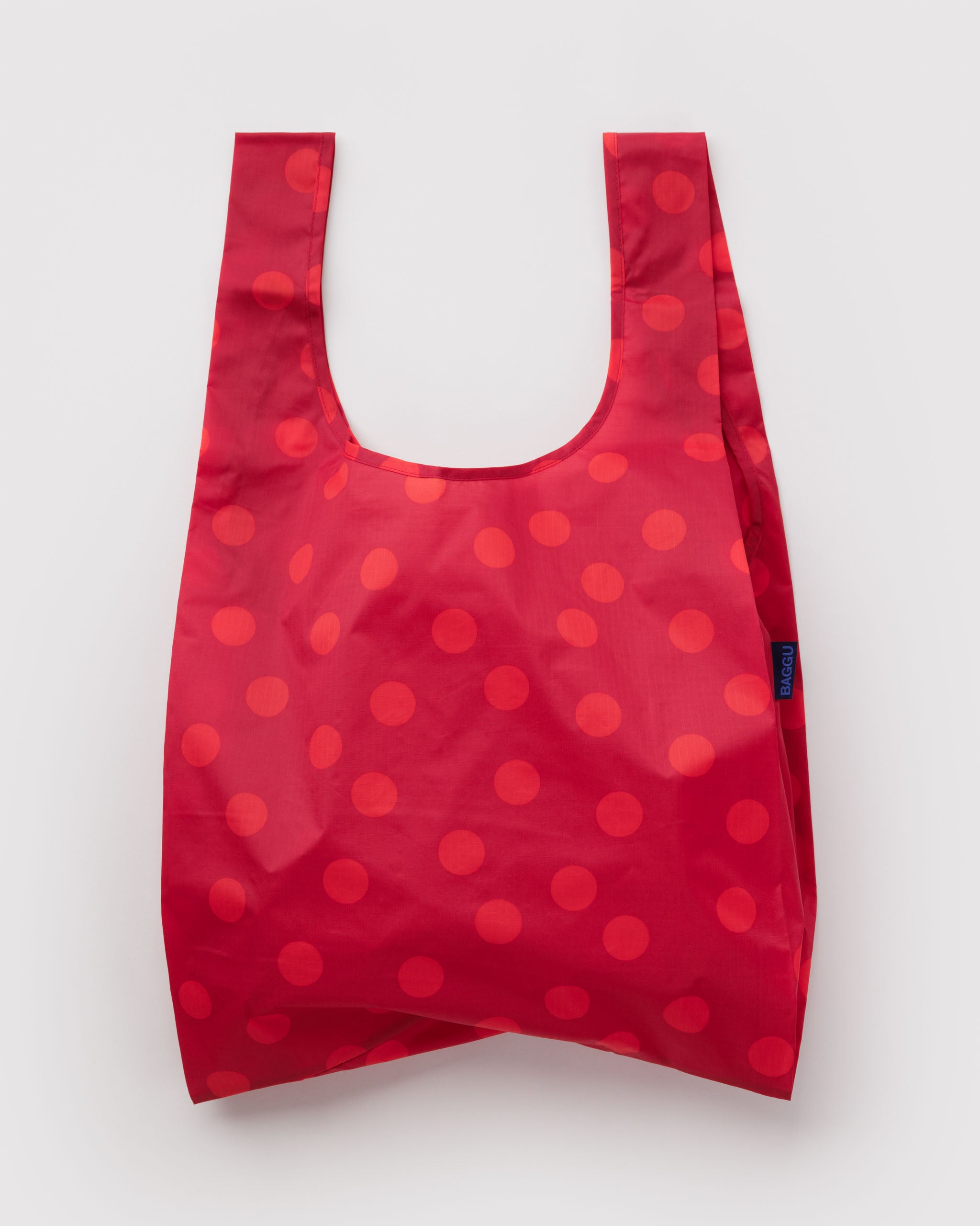 Standard Baggu Bag - Red Polka Dot. Reusable shopping tote with red background and lighter red polka dot pattern.