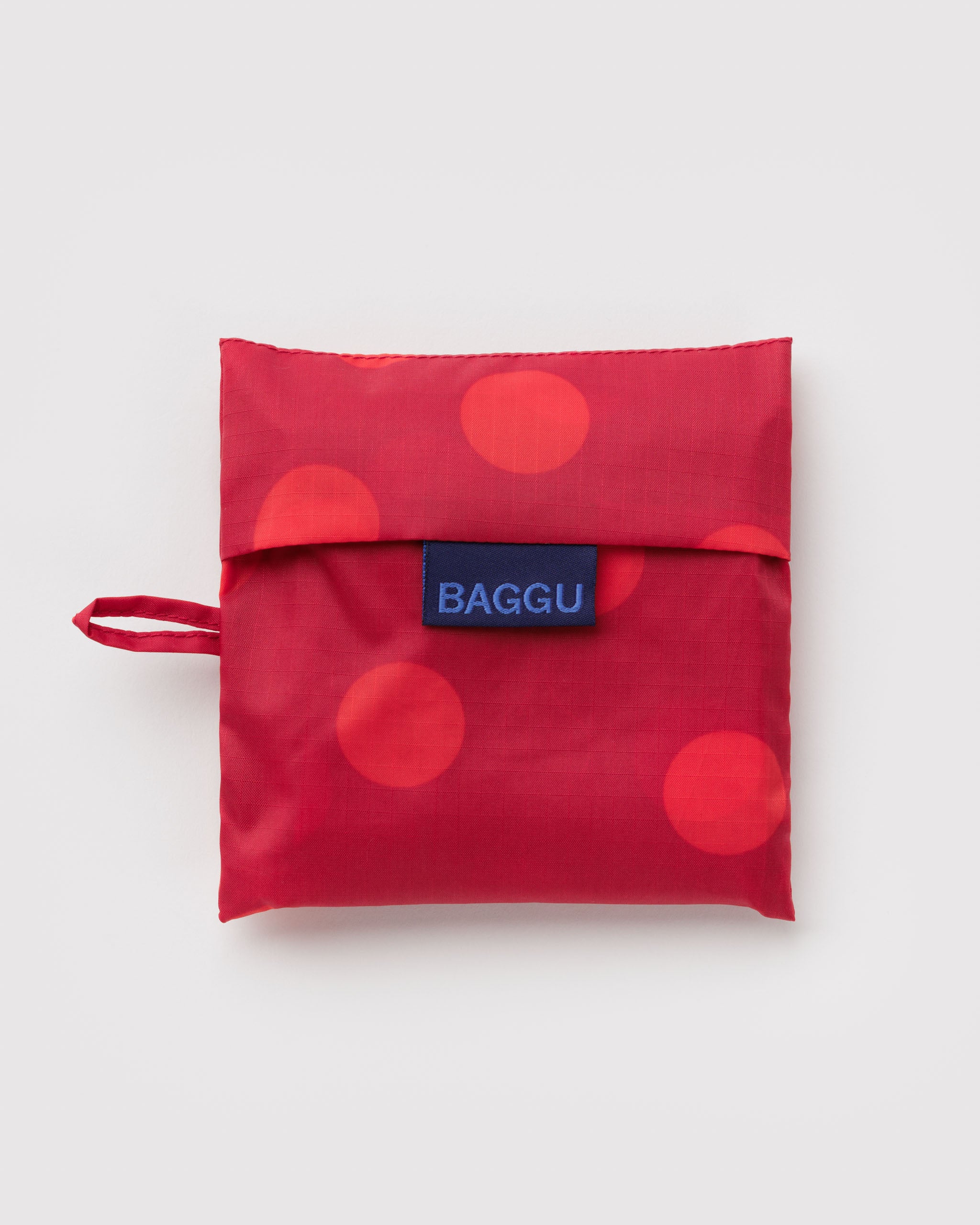 Standard Baggu Bag - Red Polka Dot. Reusable shopping tote folded up in its compact square case. 